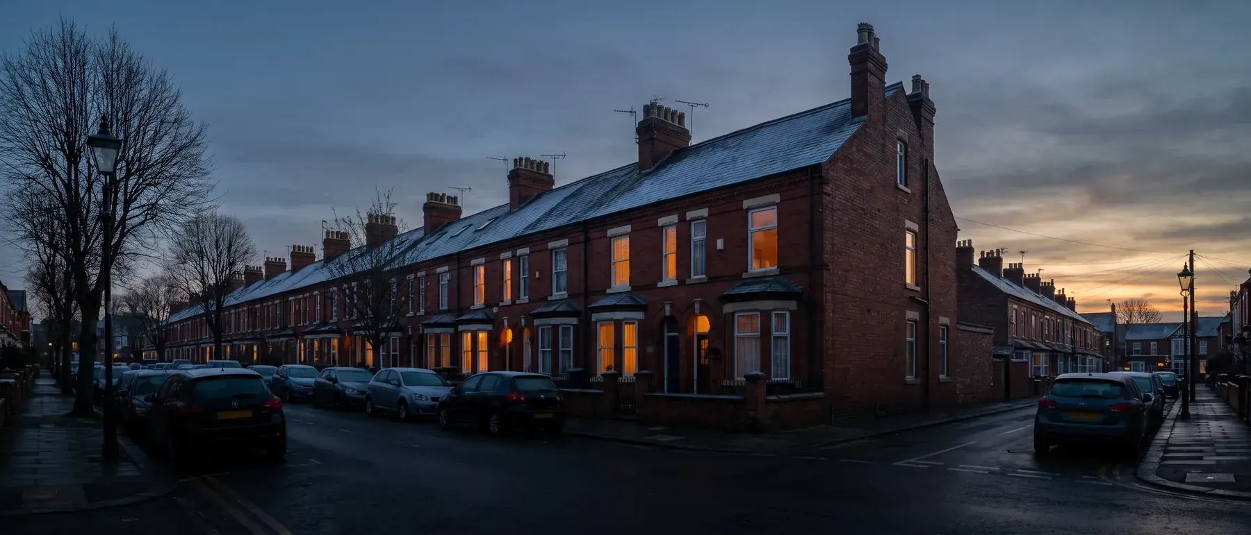 Red-brick terraced houses at winter dusk, the kind of UK home an insulation grant helps keep warm